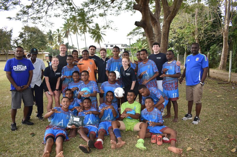 The KFK team with a junior football club in Fiji, players holding new balls and kit