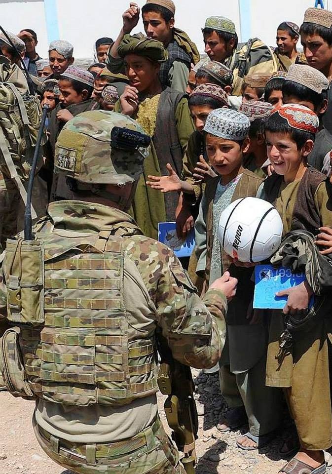 An Australian soldier hands a soccer ball to children at a school in Tarin Kot, Afghanistan